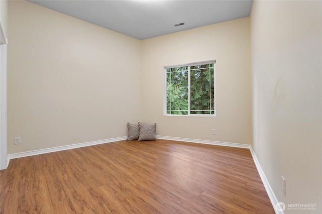 spare room featuring baseboards, visible vents, and wood finished floors