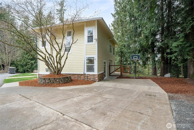 view of side of home with stone siding and a gate