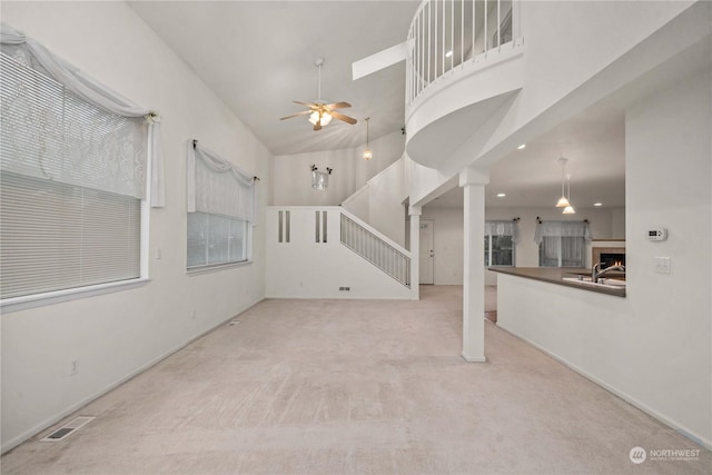 unfurnished living room featuring light carpet, high vaulted ceiling, and ceiling fan