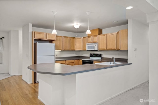 kitchen with white appliances, sink, hanging light fixtures, light hardwood / wood-style flooring, and kitchen peninsula