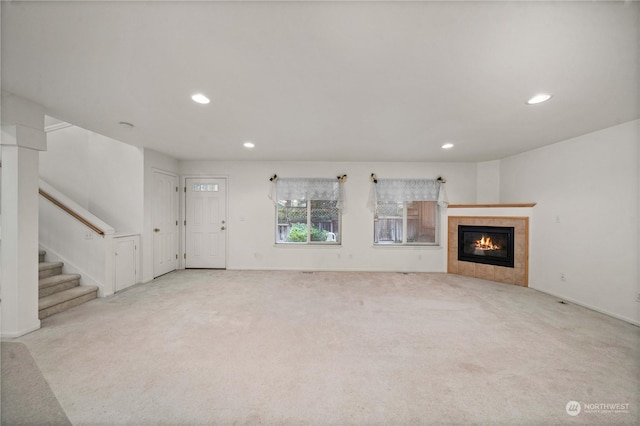 unfurnished living room with a tile fireplace and light carpet