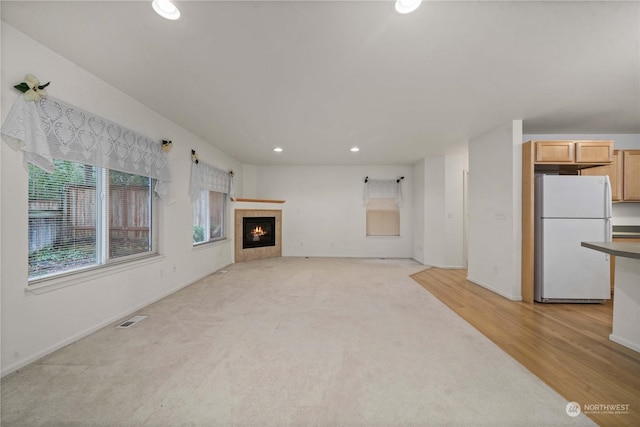 unfurnished living room with a fireplace and light colored carpet