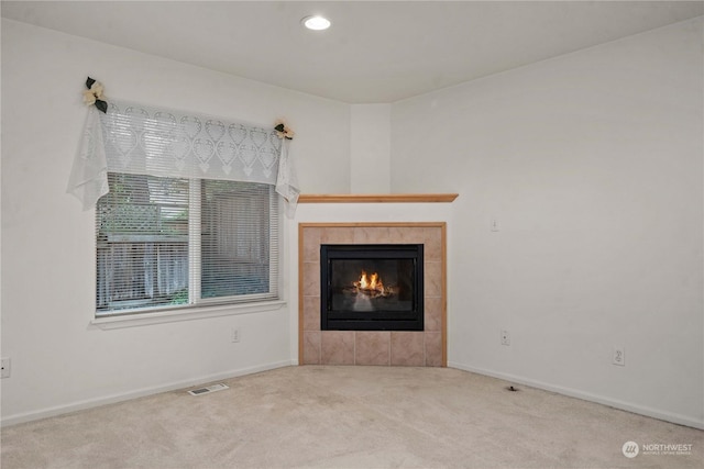 unfurnished living room with a tiled fireplace and carpet floors