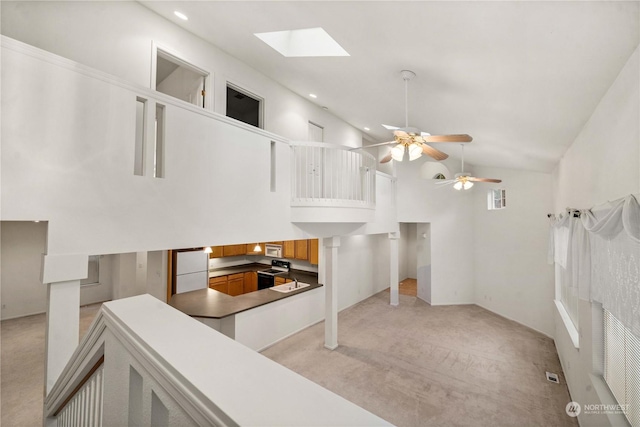 interior space with light carpet, a skylight, white appliances, ceiling fan, and high vaulted ceiling