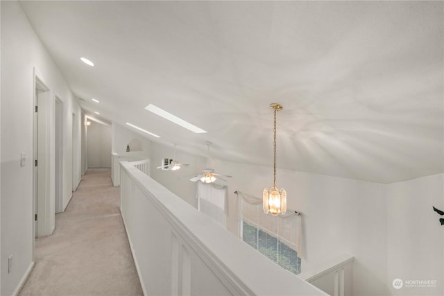 corridor featuring lofted ceiling with skylight and light carpet