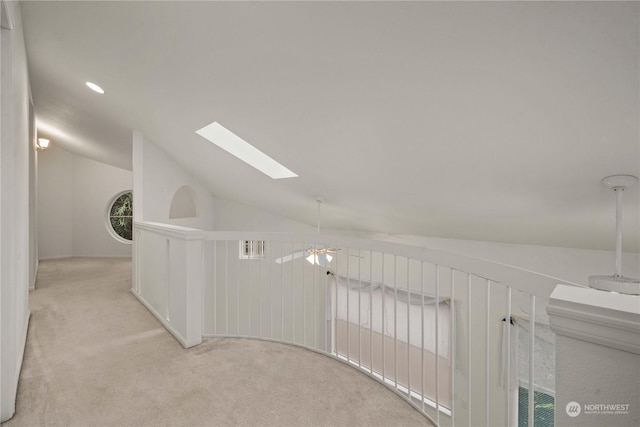 corridor featuring vaulted ceiling with skylight and light colored carpet