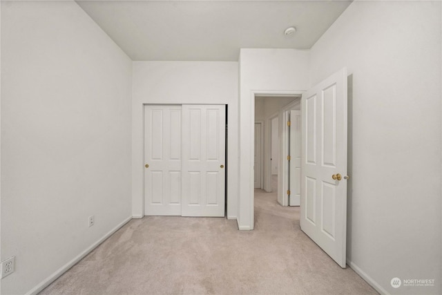 unfurnished bedroom with light colored carpet and a closet