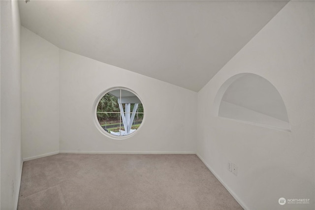 carpeted spare room with vaulted ceiling