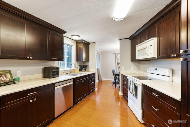 kitchen featuring dark brown cabinets, light wood-type flooring, white appliances, and sink