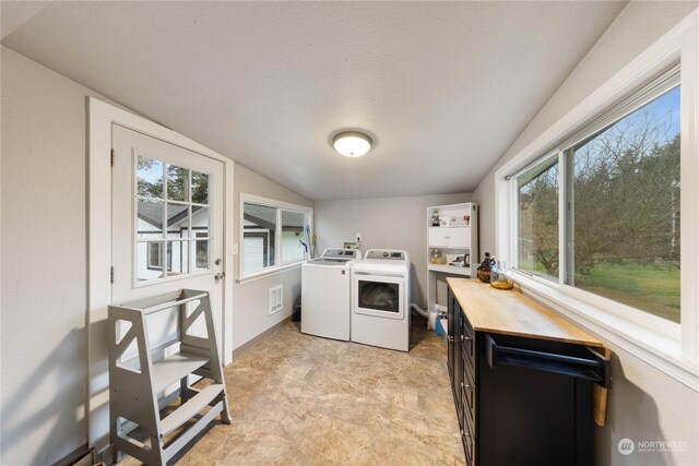 laundry room with a textured ceiling, washer and clothes dryer, and plenty of natural light