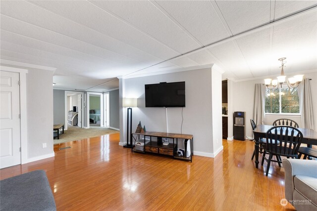 living room featuring hardwood / wood-style flooring, a notable chandelier, and ornamental molding