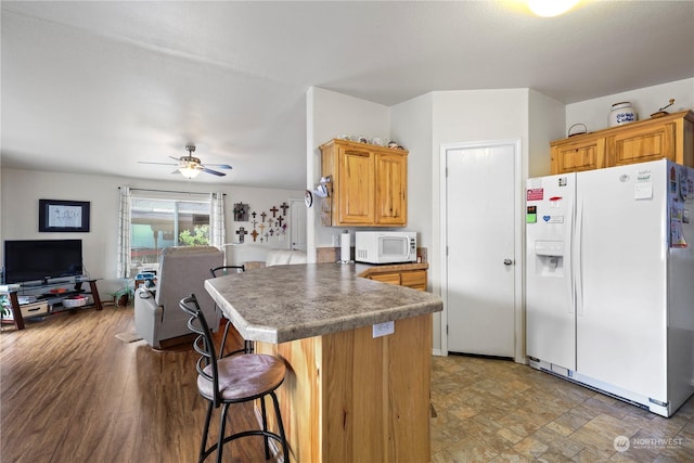 kitchen featuring ceiling fan, a kitchen bar, white appliances, and kitchen peninsula