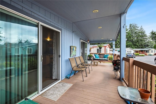 wooden terrace featuring covered porch and an outdoor hangout area