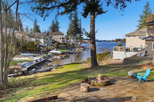 exterior space featuring a deck with water view, a fire pit, and a dock