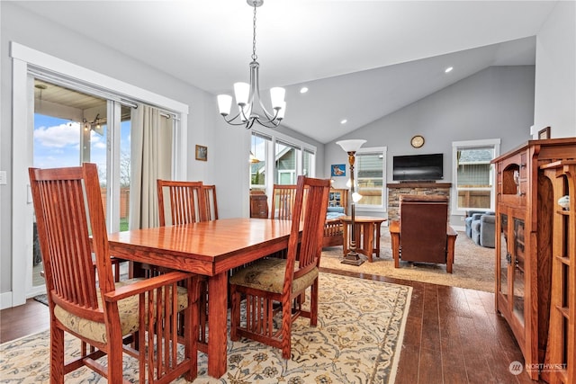 dining area with hardwood / wood-style flooring, an inviting chandelier, and lofted ceiling