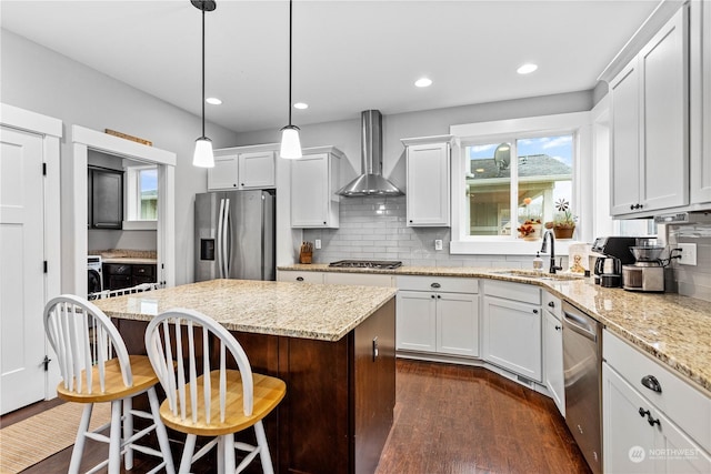 kitchen with white cabinetry, a center island, sink, wall chimney exhaust hood, and appliances with stainless steel finishes