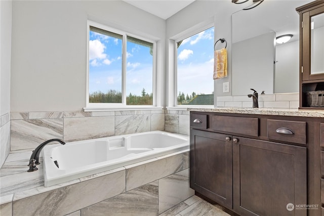 bathroom with tiled tub and vanity