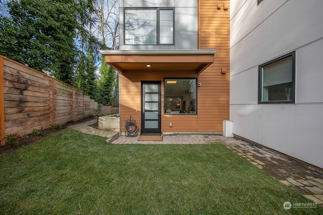 view of exterior entry featuring a yard and a patio