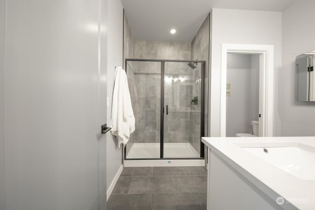 bathroom with tile patterned flooring, vanity, toilet, and a shower with shower door