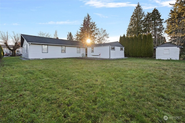 rear view of property with a storage unit and a yard