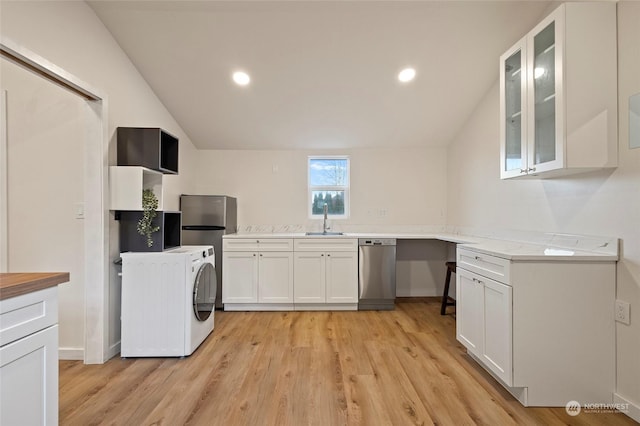 kitchen with dishwasher, washer / dryer, sink, white cabinets, and lofted ceiling