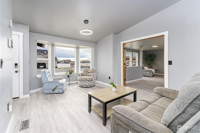 living room featuring a fireplace, vaulted ceiling, and light wood-type flooring