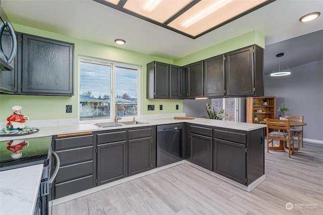 kitchen with kitchen peninsula, sink, stainless steel dishwasher, and light hardwood / wood-style floors