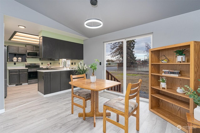 dining space with light hardwood / wood-style floors, lofted ceiling, and sink