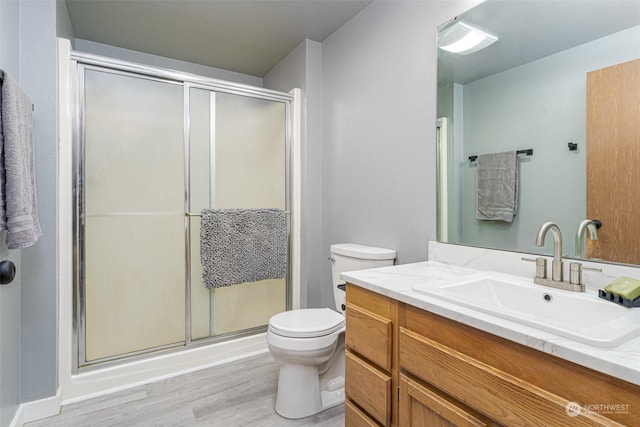 bathroom with hardwood / wood-style floors, vanity, toilet, and an enclosed shower