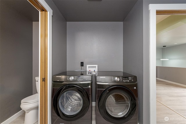 clothes washing area featuring washing machine and dryer and light hardwood / wood-style flooring