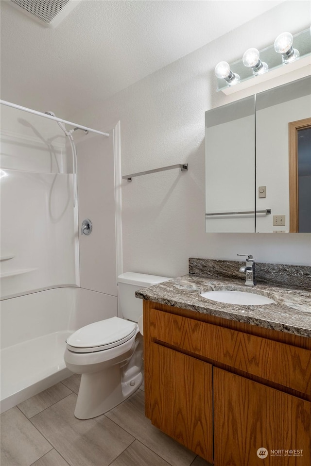 bathroom featuring vanity, toilet, and walk in shower