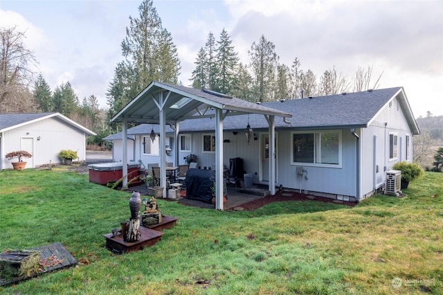 back of property featuring a yard, cooling unit, a patio, and a hot tub