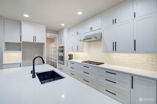 kitchen with stainless steel appliances, a sink, light countertops, under cabinet range hood, and white cabinetry