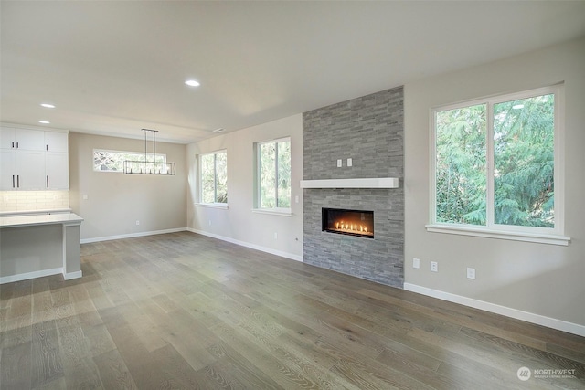 unfurnished living room with a large fireplace, baseboards, and light wood-style flooring