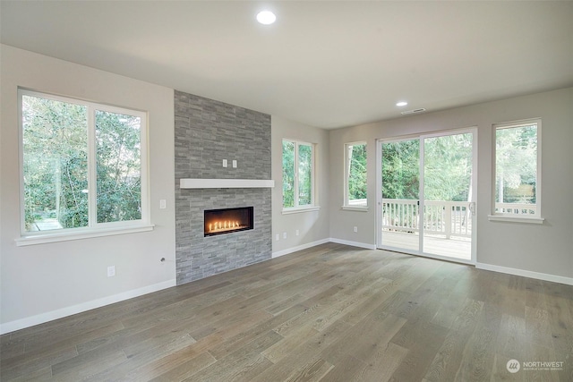 unfurnished living room with visible vents, baseboards, recessed lighting, a fireplace, and wood finished floors