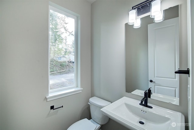 bathroom featuring plenty of natural light, toilet, and a sink