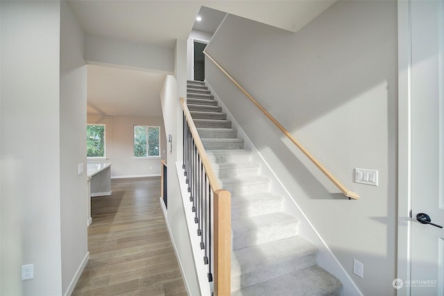 stairway with wood finished floors and baseboards