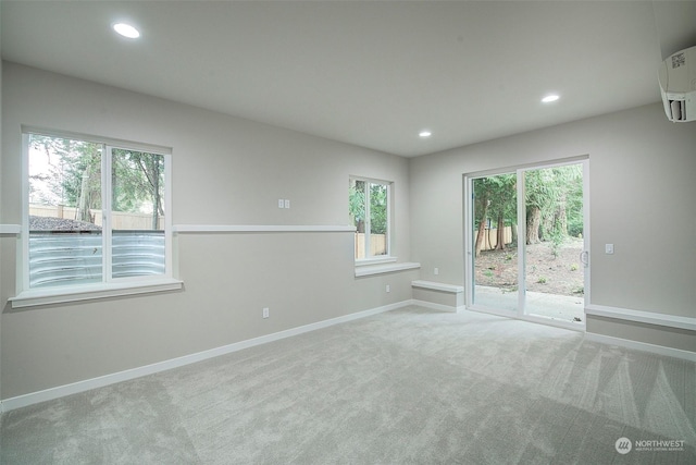 spare room with a wall unit AC, recessed lighting, baseboards, and carpet floors