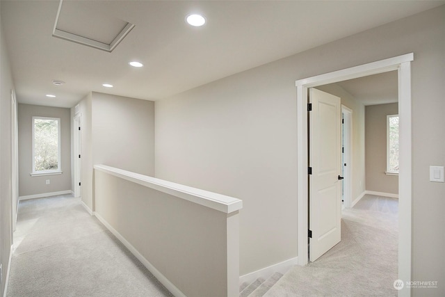 hallway featuring recessed lighting, light colored carpet, baseboards, and an upstairs landing