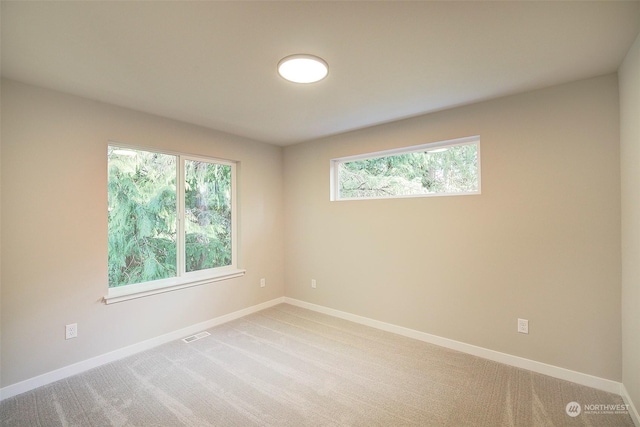 spare room with visible vents, light colored carpet, and baseboards