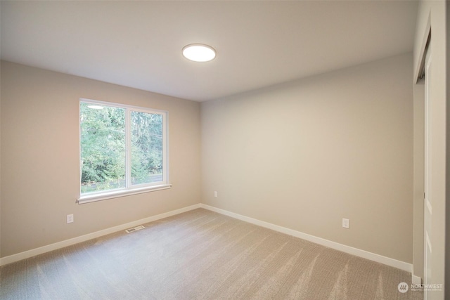 spare room featuring visible vents, baseboards, and light carpet