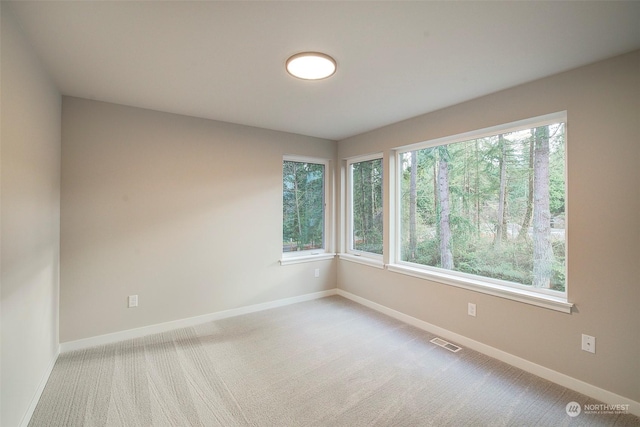 unfurnished room featuring visible vents, baseboards, and light colored carpet