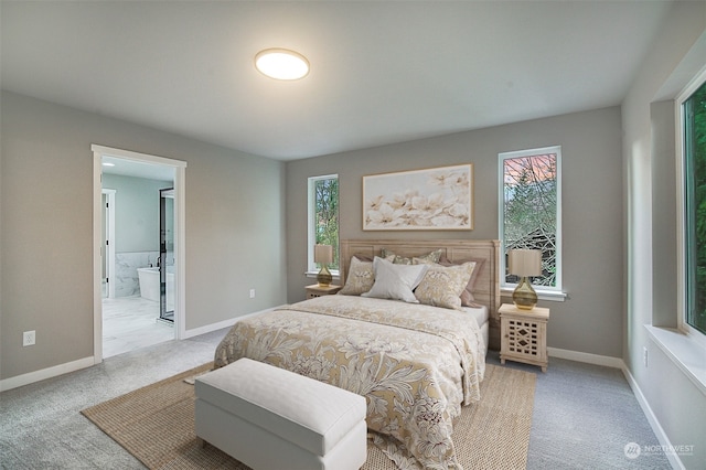 bedroom featuring light colored carpet, baseboards, and connected bathroom