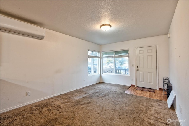 foyer entrance with a wall mounted air conditioner, a textured ceiling, and carpet flooring