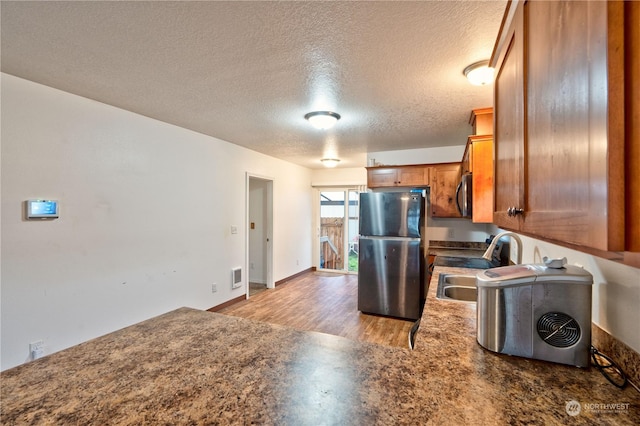 kitchen featuring a textured ceiling, stainless steel appliances, light hardwood / wood-style flooring, and sink