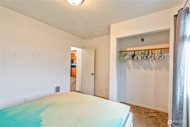 bedroom featuring a textured ceiling, carpet floors, and a closet