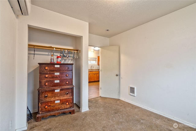 unfurnished bedroom featuring carpet flooring, a textured ceiling, and an AC wall unit