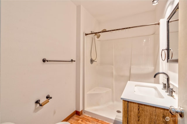 bathroom featuring toilet, vanity, hardwood / wood-style floors, and walk in shower