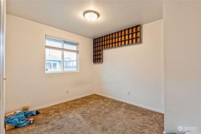 carpeted empty room featuring a textured ceiling