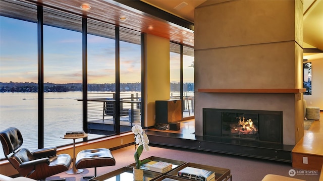 interior space featuring a water view, a warm lit fireplace, and carpet